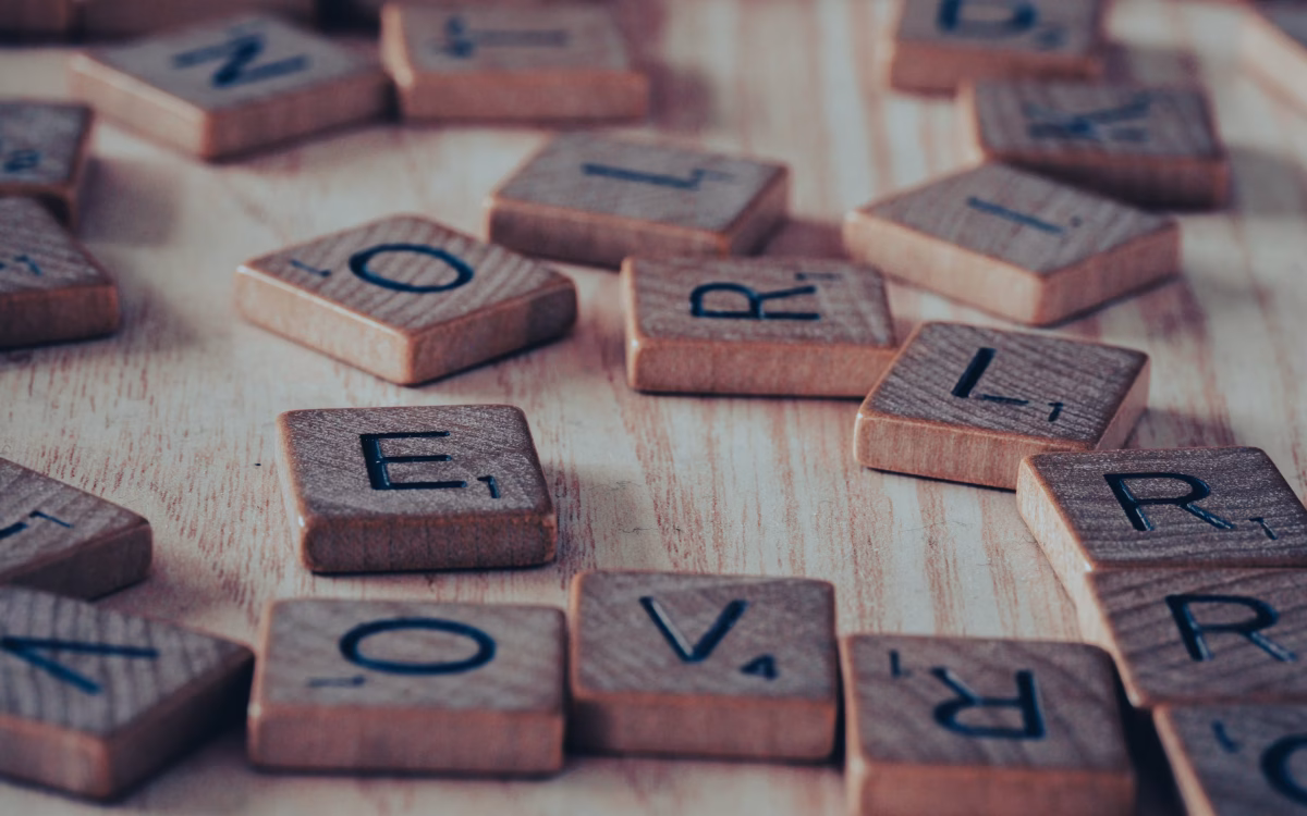 Wooden alphabet blocks spelling out descriptive words beside an open notebook — adjectives that start with s